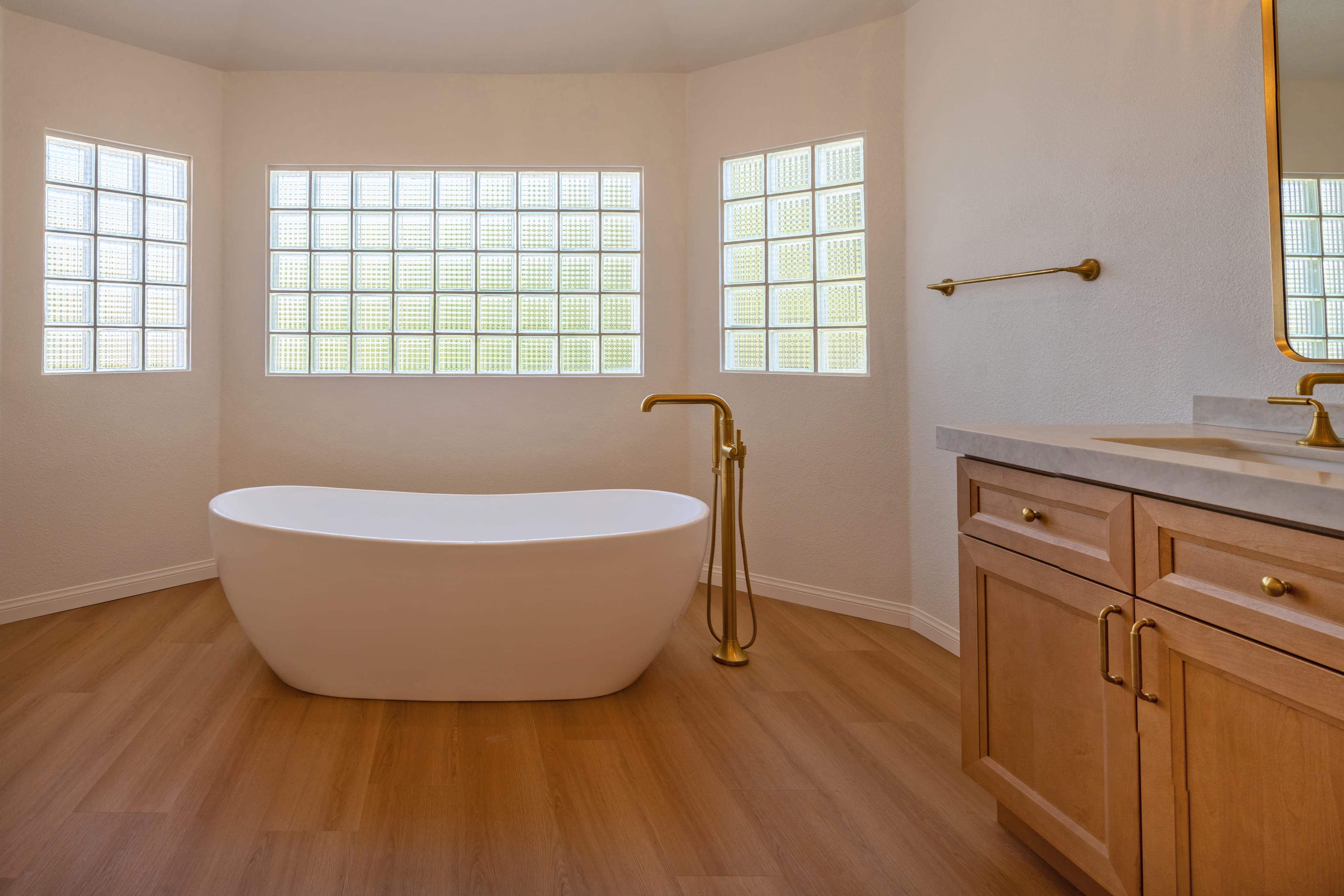 Finished master bathroom with freestanding soaking tub and gold fixtures